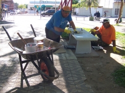 Funcionrios dos Servios Urbanos pintam um dos bancos de cimento da praa
